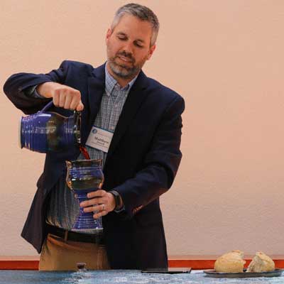 The Rev. Matthew Bussell, a member of the Presbyterian Mission Agency Board, leads those gathered in taking Communion together. Photo by Rick Jones.