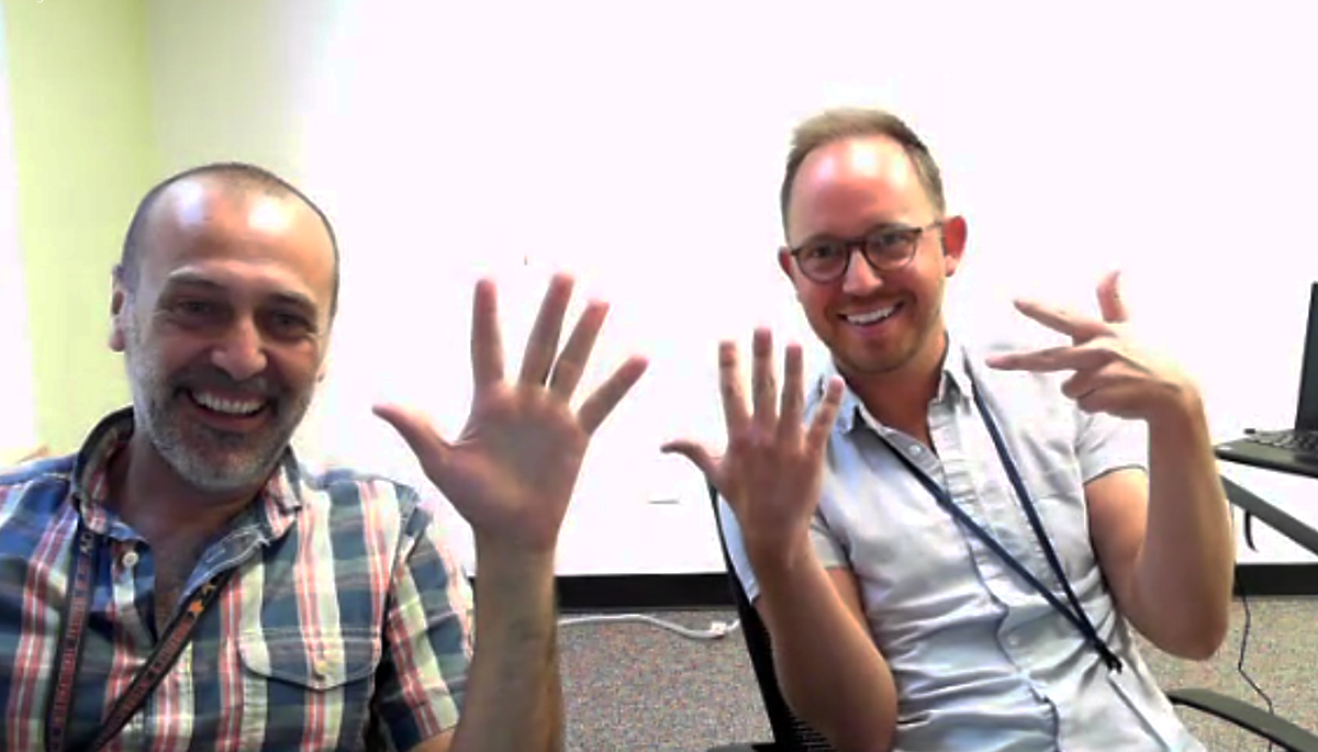 Guna (left) and Young (right) holding up fingers for each Assembly they’ve worked at, June 2022.