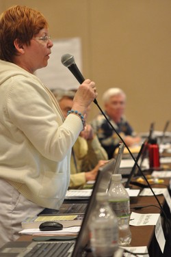 A woman speaks at a microphone 