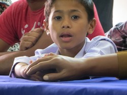 A young boy holds the prosthetic hand of a man who was injured in the garment factory collapse.