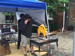 Mike Martin of RAWtools cuts the stock off a donated rifle, preparing to reforge the barrel as a garden tool at a demonstration for the Festival of Faiths.