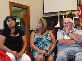 Two women and a man, sitting down as one woman talks.