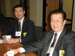 Two men in suits sitting at a table.