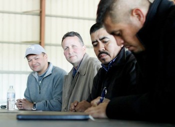 Walmart representatives John Amaya (left), Tom Leech (center) and CIW's Lucas Benitez look on as CIW's Gerardo Reyes Chavez (far right) signs historic agreement at a Lipman Produce farm outside of Immokalee.