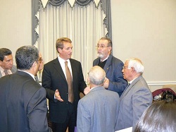 A group of men in suits, speaking in a hall.