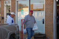 A man walks past another man holding plastic bags.