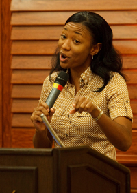 The Rev. Alice Ridgill speaking, holding a microphone.