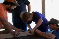 Young people hammer into wood.