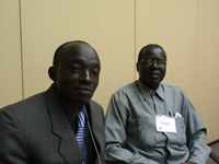 Two men, sitting, looking frontward (as to a camera).