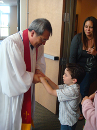 Jason Ku, in vestments, greets a boy.