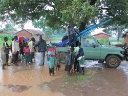 Malawians offload supplies near a site for a hand-drilled borehole, supervised by Jim McGill.