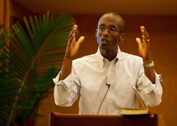 A man at a lectern gives a passionate sermon using his hands.