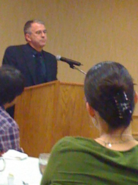 A man speaking to a group from a lectern.