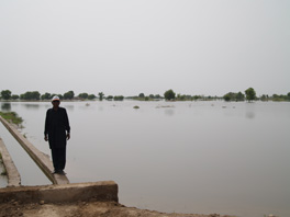 A man walking on a concrete barrier near a flooded area.