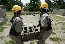 Two women carrying blocks of concrete.