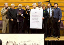 A group of people standing on a platform as one holds a large deed.