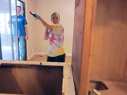 The Rev. Catherine Renken, pastor of Kirkwood Presbyterian Church, uses a sledgehammer to demolish the old kitchen in Promise House.