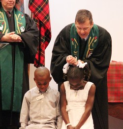 The Rev. John Odom, pastor of Starmount Presbyterian Church baptizes Marceline Kilassa and Benjamin Kibfoulwa, with teaching elder Kathryn Campbell, associate pastor (left). Both children received help through Black Child Development Institute.