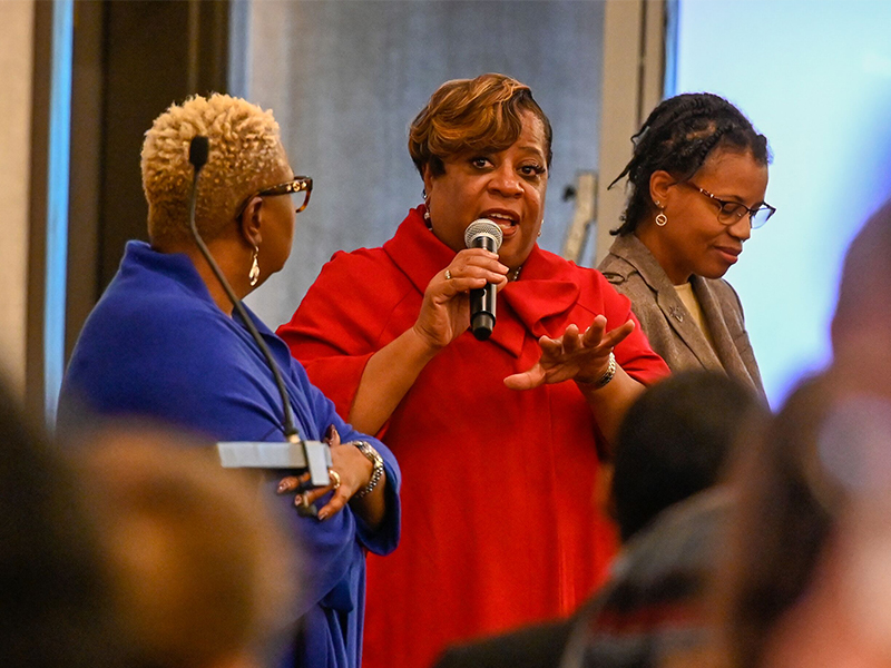 In between Monica Walker and Dr. Debbie Stroman, the Rev. Dr. Diane Moffett, president and executive director of the Presbyterian Mission Agency, speaks during staff development day. Photo by Rich Copley