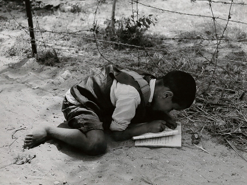 Child studying on the unmarked border between Israel and the Gaza Beach refugee camp, 1959. From Church World Service records at the Presbyterian Historical Society.