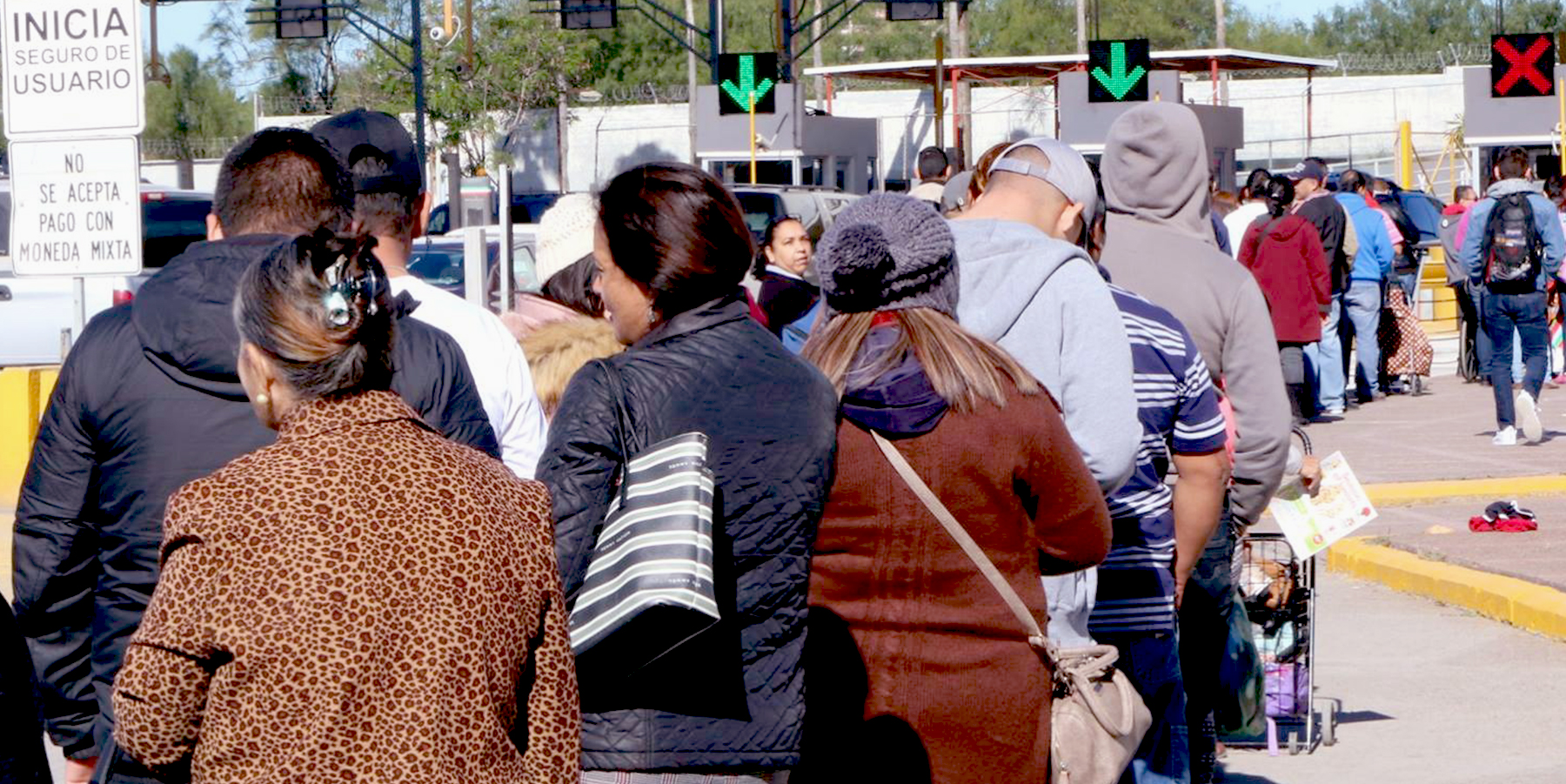 Image of people waiting in line at the border between Mexico and the United States. 